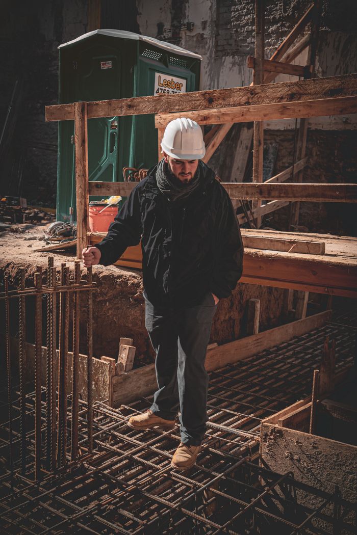 services-01 A construction worker in a hard hat inspects steel reinforcement bars on site.