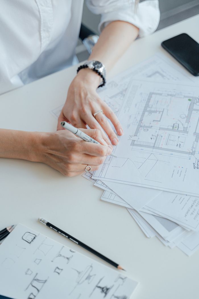 services-02 An architect writes notes on design plans while sitting at a desk, focusing on details.