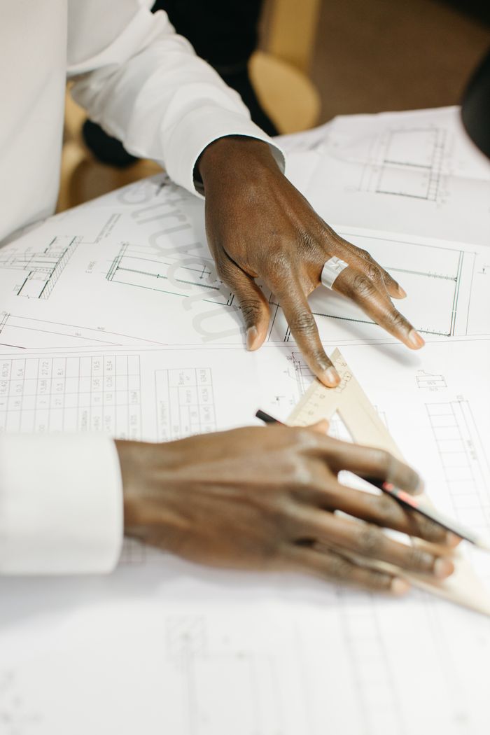 services-img Close-up of a person drafting architectural plans with precision tools.